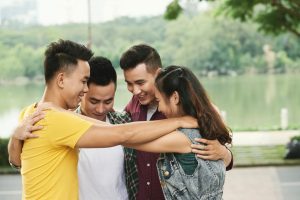Group of hugging happy friends standing outdoors
